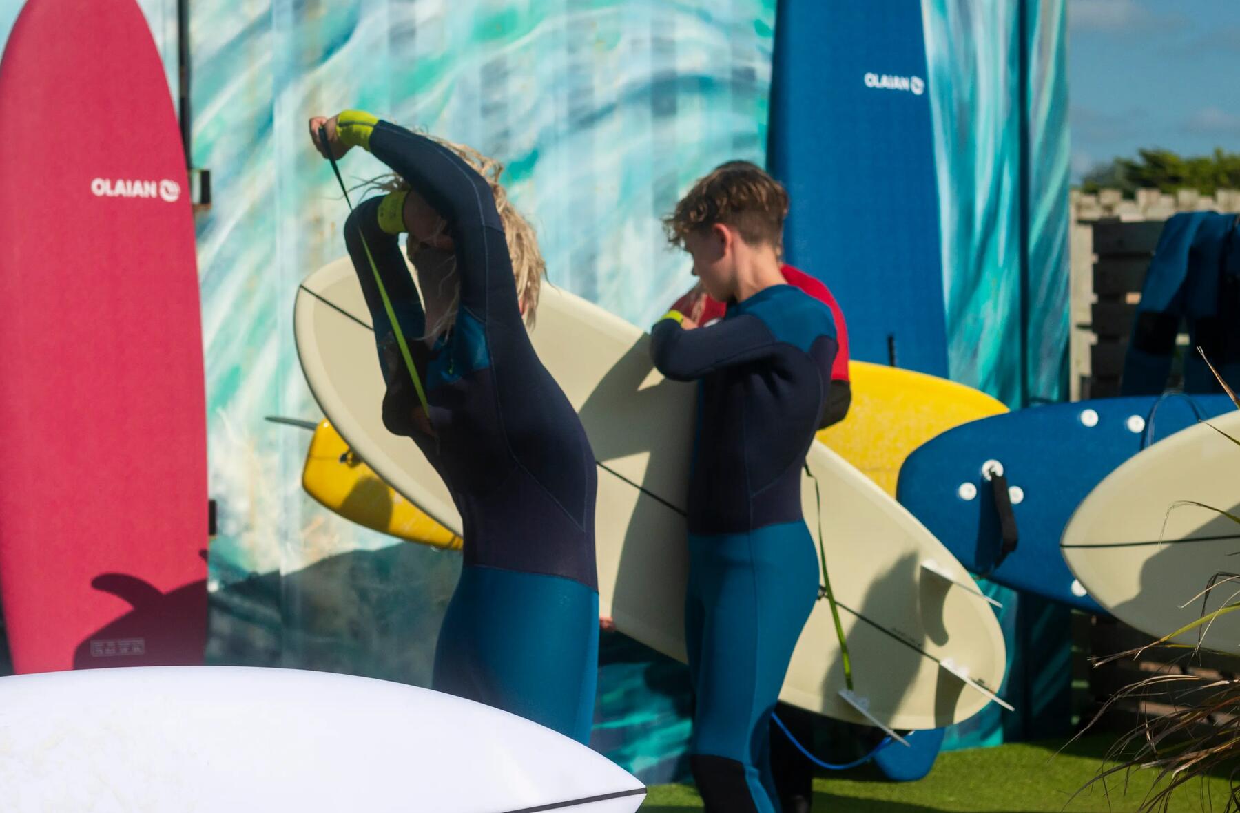 Two youngsters in the process of putting on their wetsuit.
