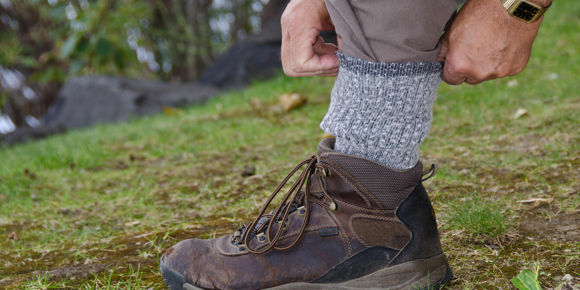 un randonneur rentre son pantalon dans sa chaussette