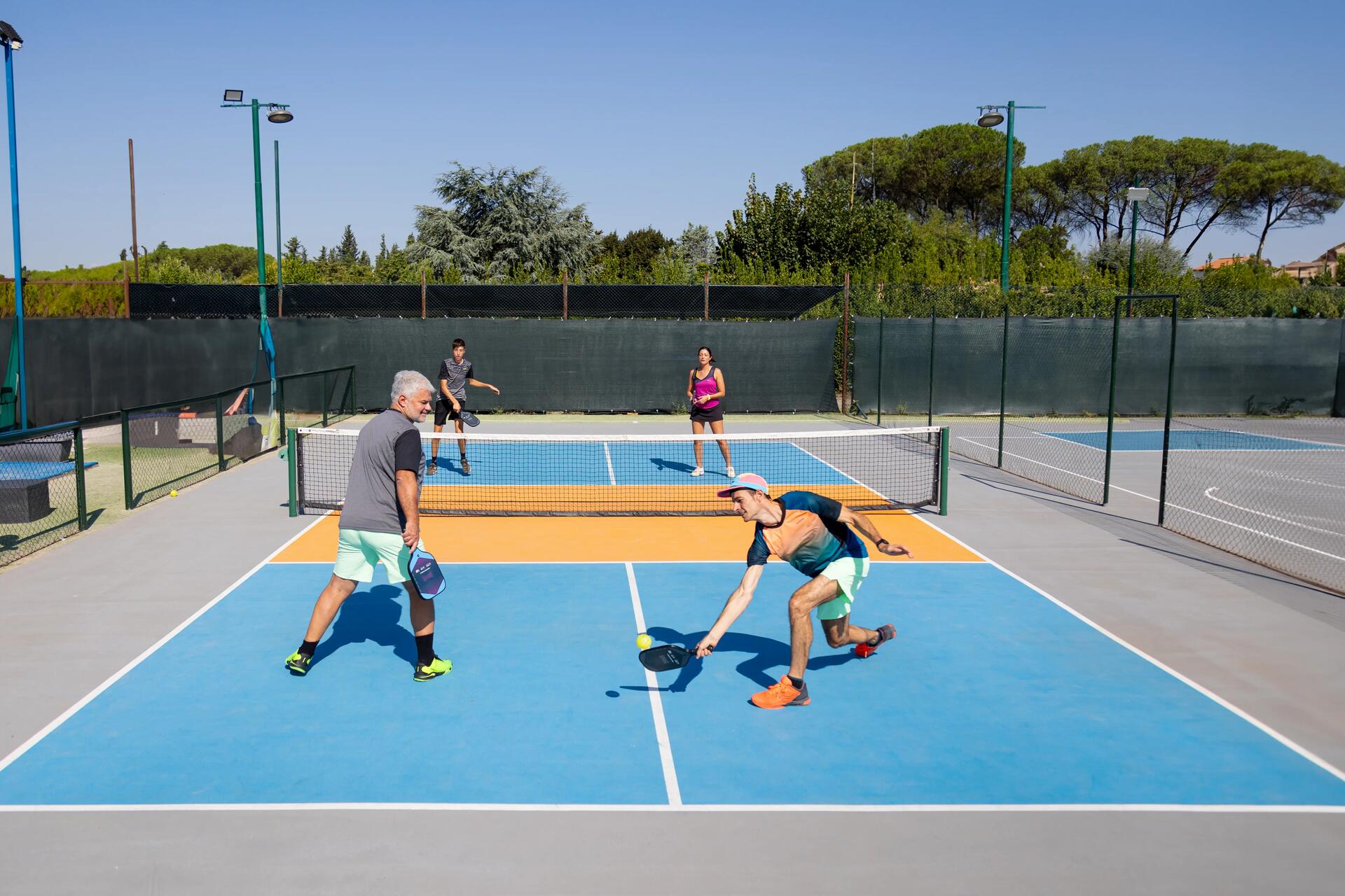 Grupa ludzi w strojach sportowych grająca w pickleballa