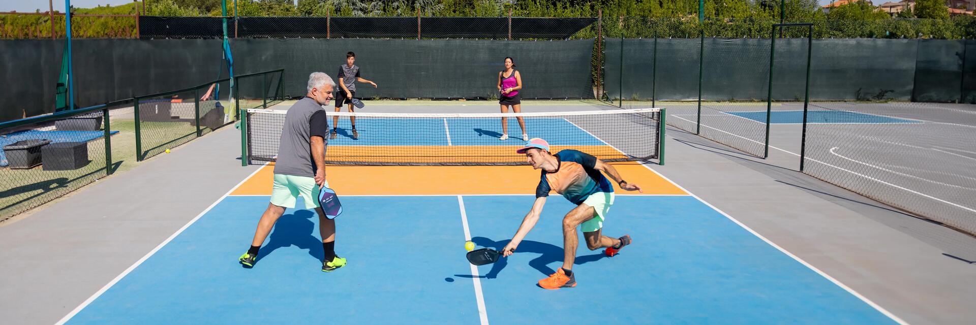 Czworo ludzi w strojach sportowych grająca w pickleballa na korcie