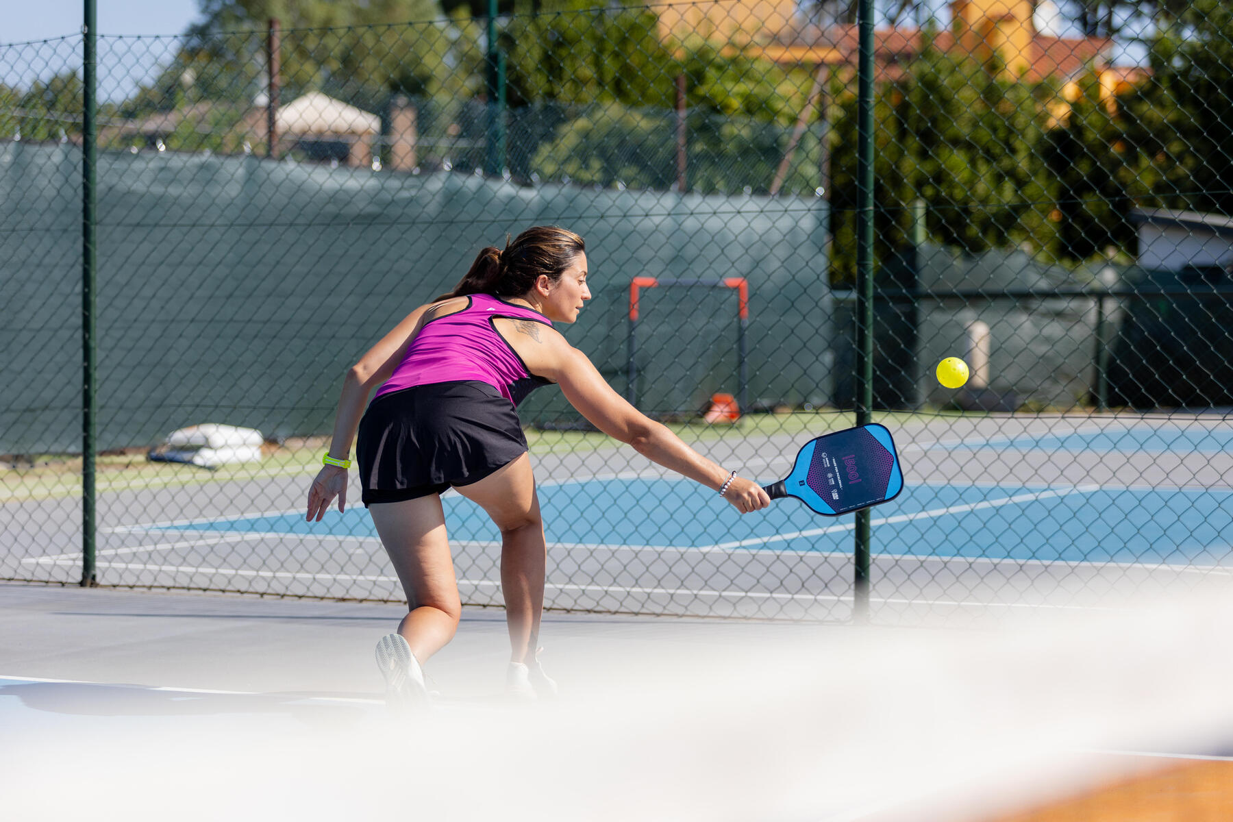 Kobieta w stroju sportowym odbijająca piłkę grająca w pickleballa na korcie na świeżym powietrzu