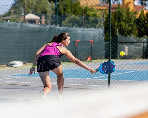 Kobieta w stroju sportowym odbijająca piłkę grająca w pickleballa na korcie na świeżym powietrzu