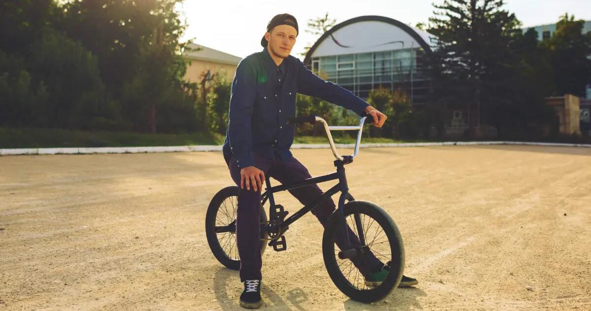Mężczyzna w czapce z daszkiem siedzący na rowerze bmx