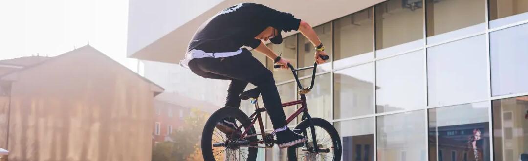 mężczyzna w butach na BMX wykonujący trik na rowerze