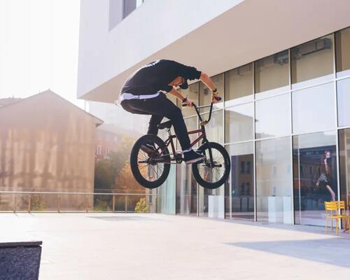 mężczyzna w butach na BMX wykonujący trik na rowerze