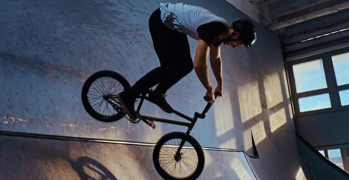 mężczyzna w kasku rowerowym zjeżdżający z rampy na rowerze  BMX