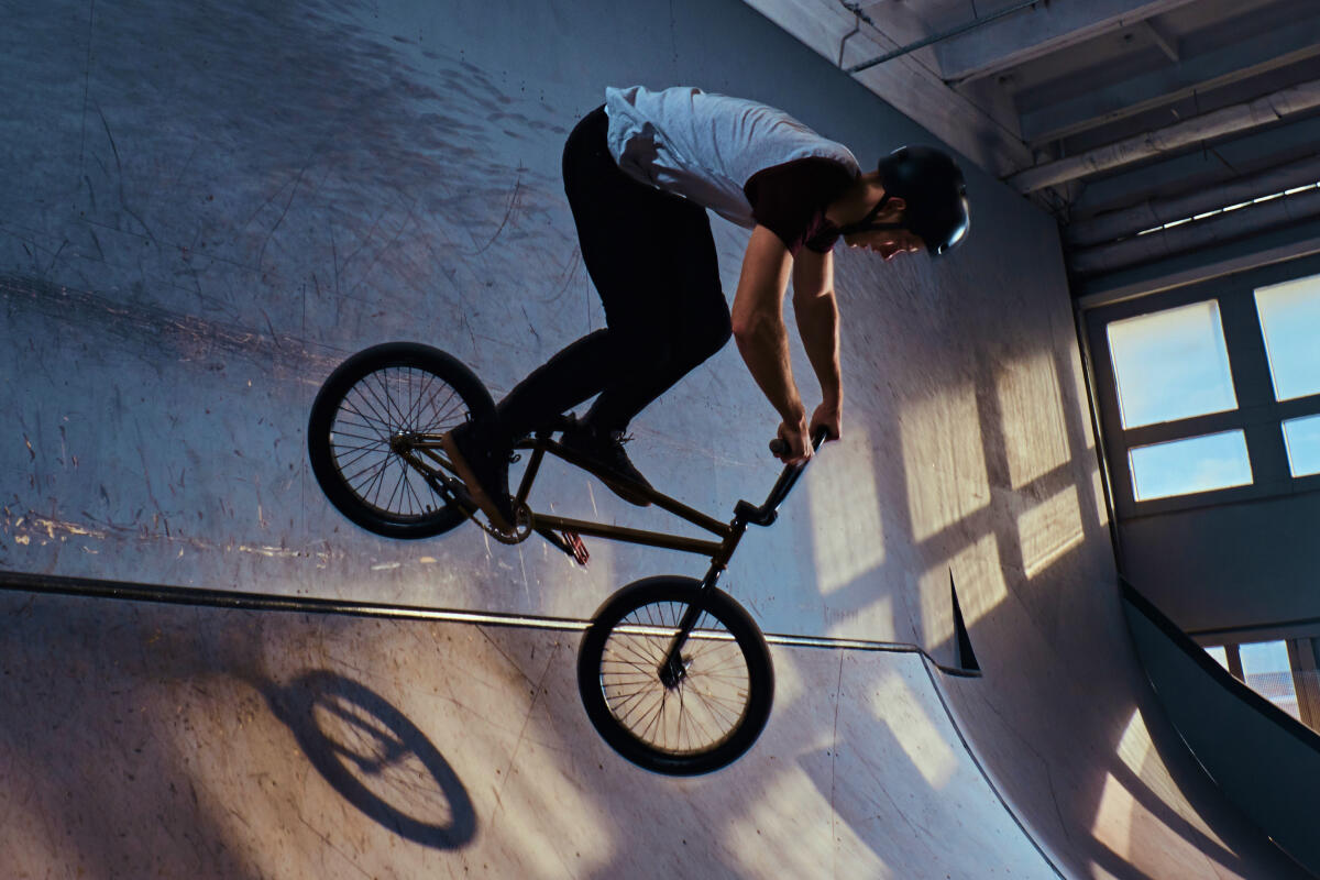 Chłopak w kasku jadący rowerem bmx po rampie rowerowej