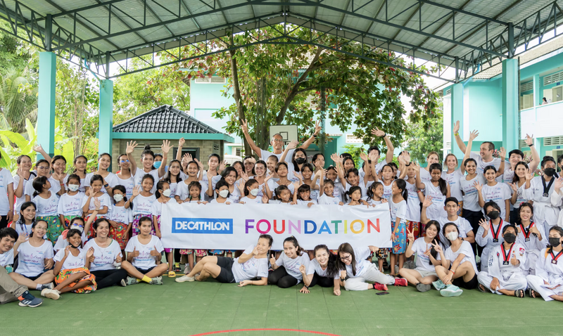 Un gruppo di bambini posa con lo striscione della fondazione Decathlon