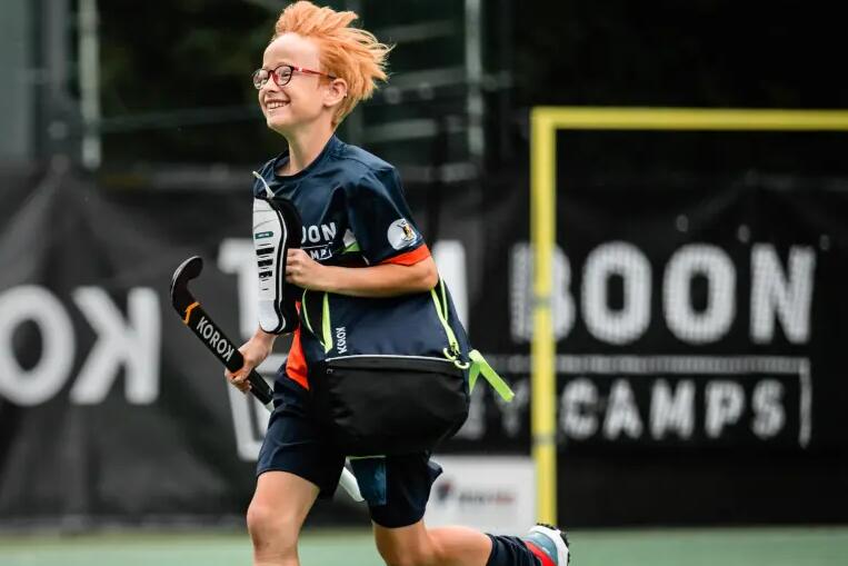 Een kindje op een hockeyveld met hockeymateriaal van Decathlon vast (Korok)