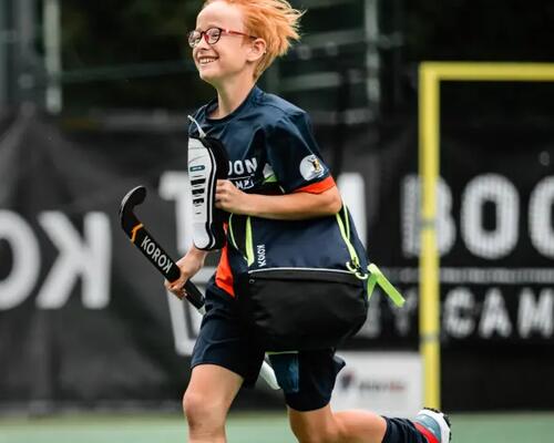 Een kindje op een hockeyveld met hockeymateriaal van Decathlon vast (Korok)