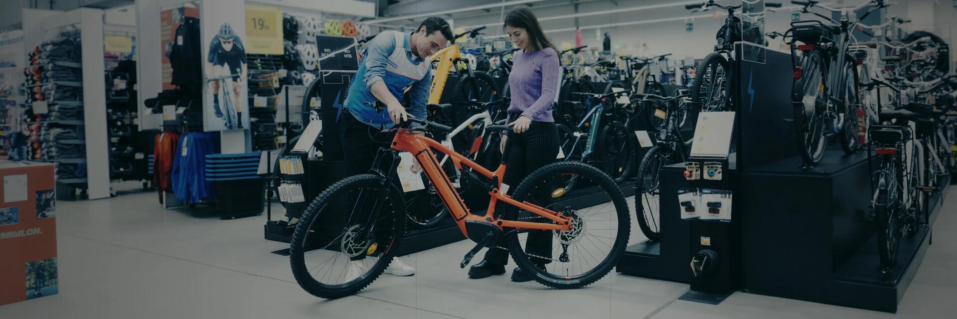 Kobieta oglądająca rower w sklepie w towarzystwie pracownika sklepu