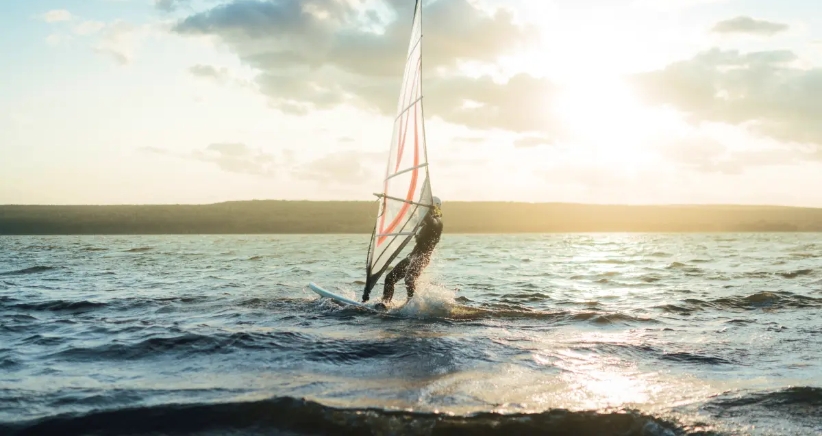 osoba w piance do pływania uprawiająca windsurfing
