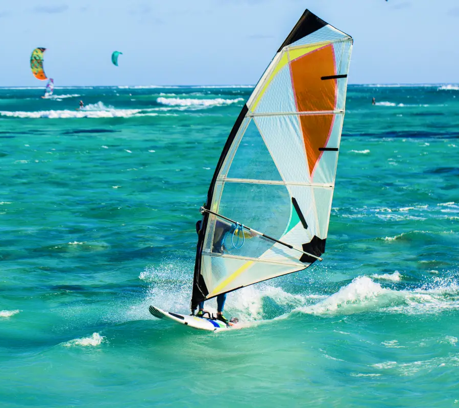 Osoba pływająca na desce windsurfingowej z żaglem windsurfingowym