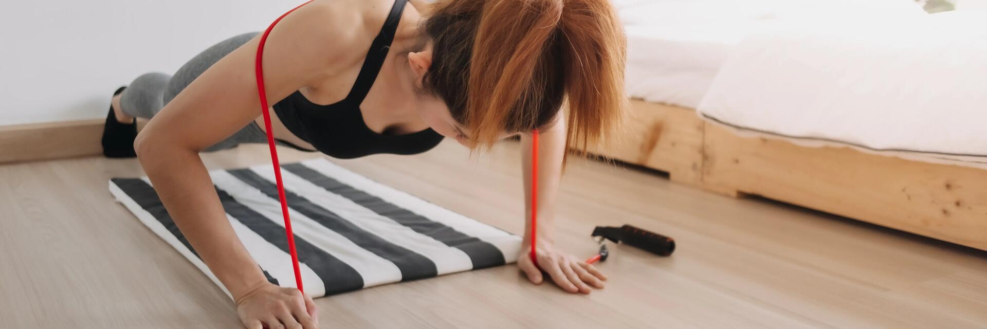 Kobieta w odzieży sportowej ćwicząca pompki z gumami na podłodze