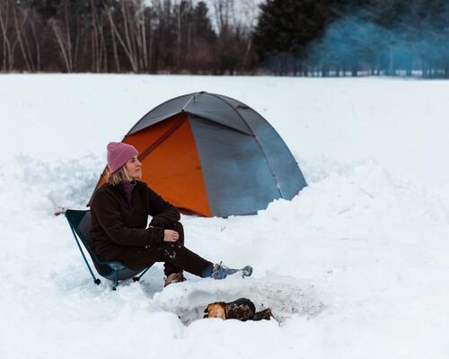 Eine Frau campt im Winter mit Zelt