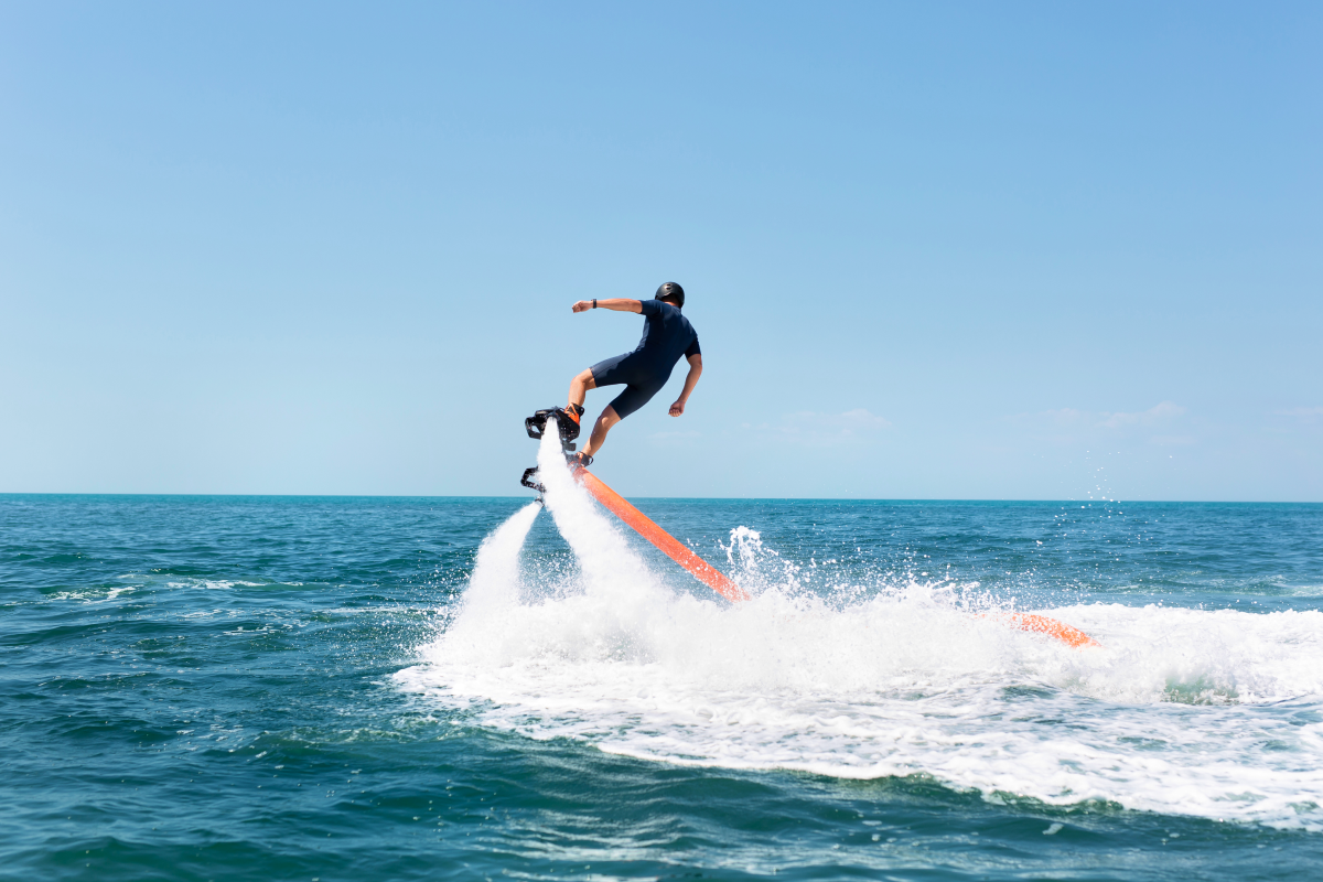 mężczyzna w kasku i stroju pływackim uprawiający flyboarding