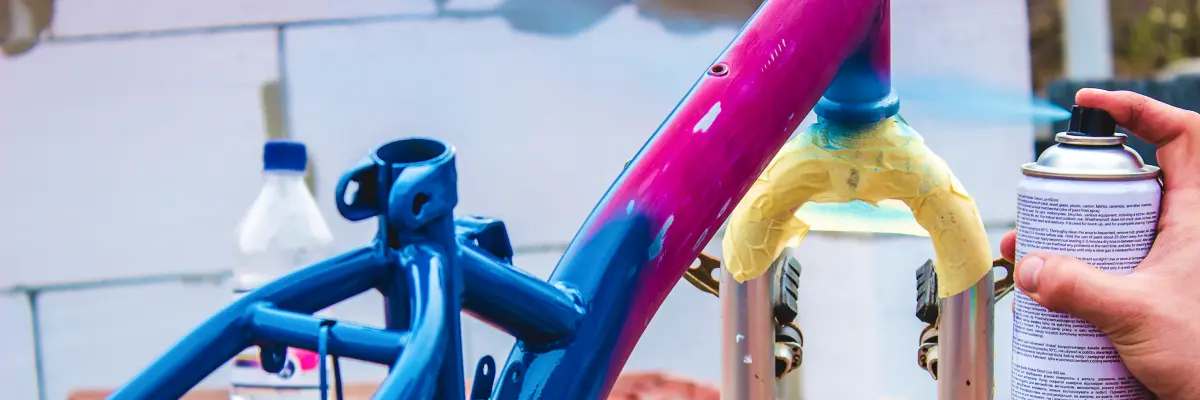 Mężczyzna malujący ramę rowerową farbą w sprayu