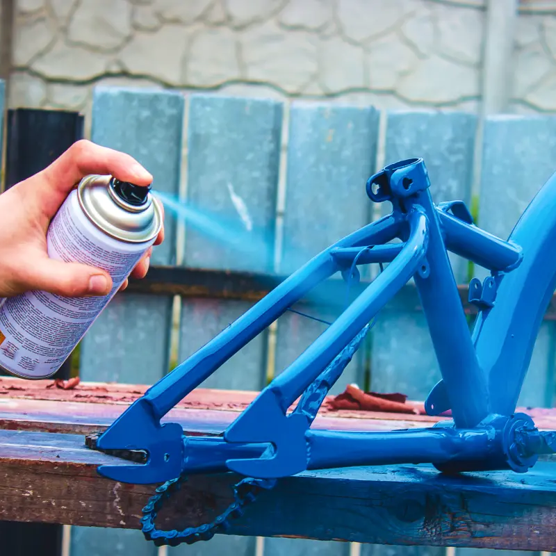 Mężczyzna używający farby w sprayu do renowacji roweru