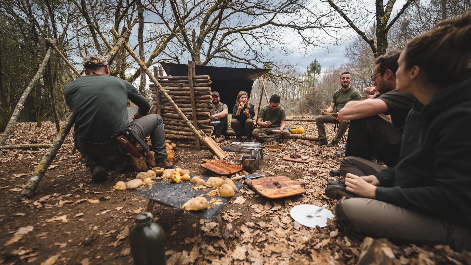 Stage de bushcraft avec Solognac : un groupe de participants monte un camp et mange