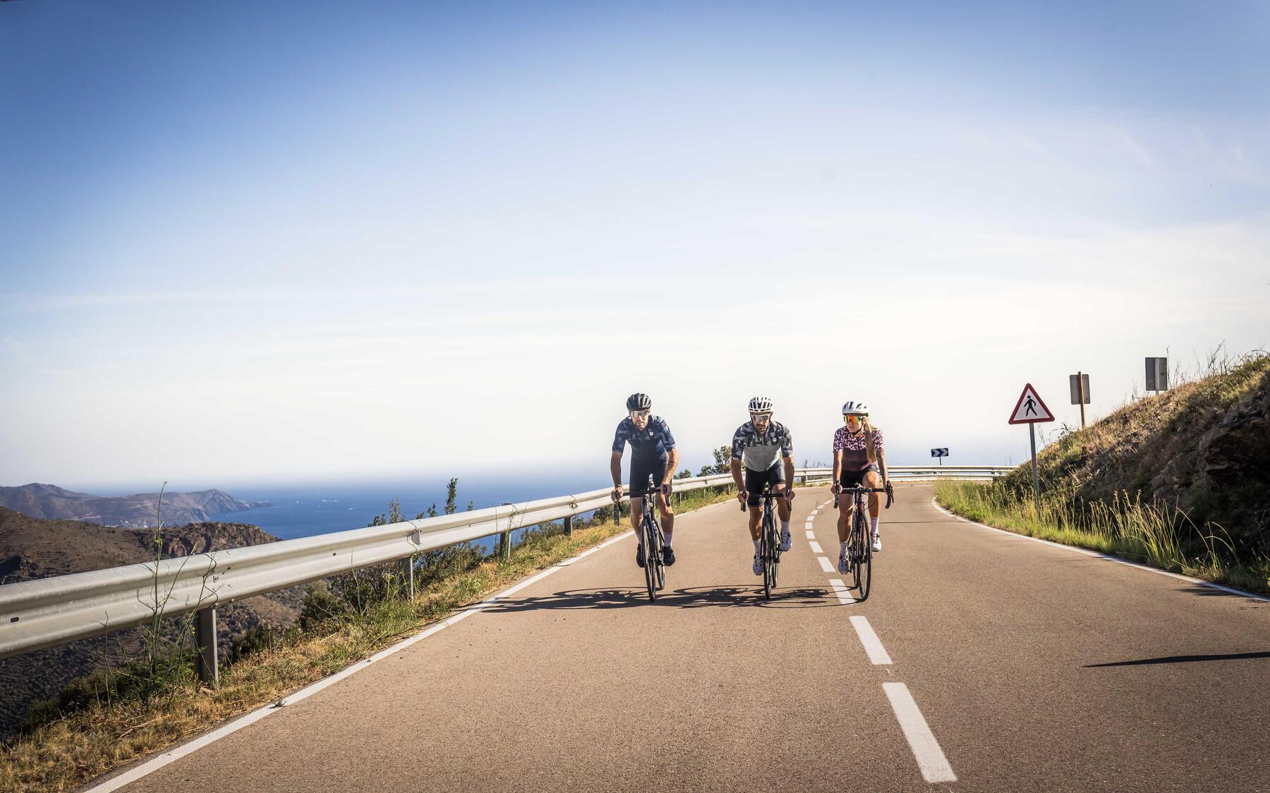 Troje rowerzystów jadących na rowerach po asfalcie