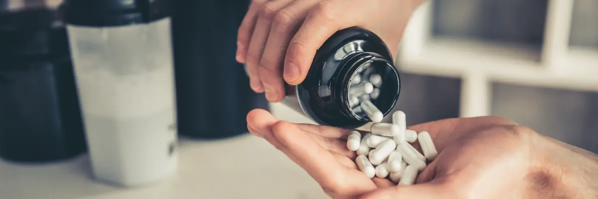 Mężczyzna wysypujący na rękę probiotyki z opakowania