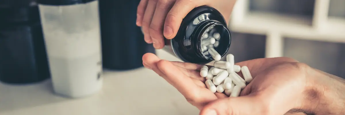Mężczyzna wysypujący na rękę probiotyki z opakowania