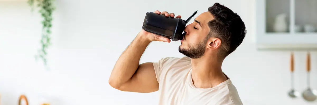 Mężczyzna pijący z bidonu zastanawiający się który suplement wziąć przed treningiem beta-alanine czy bcaa