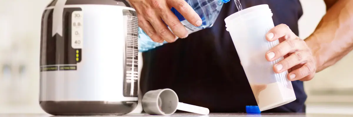 Mężczyzna przyrządzający shake proteinowy bezlaktozy przed wysiłkiem fizycznym