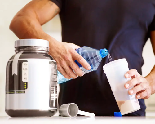 Mężczyzna przyrządzający shake proteinowy bezlaktozy przed wysiłkiem fizycznym