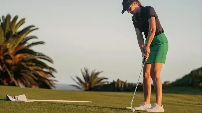 Kobieta z kijem golfowym uderzająca w piłkę