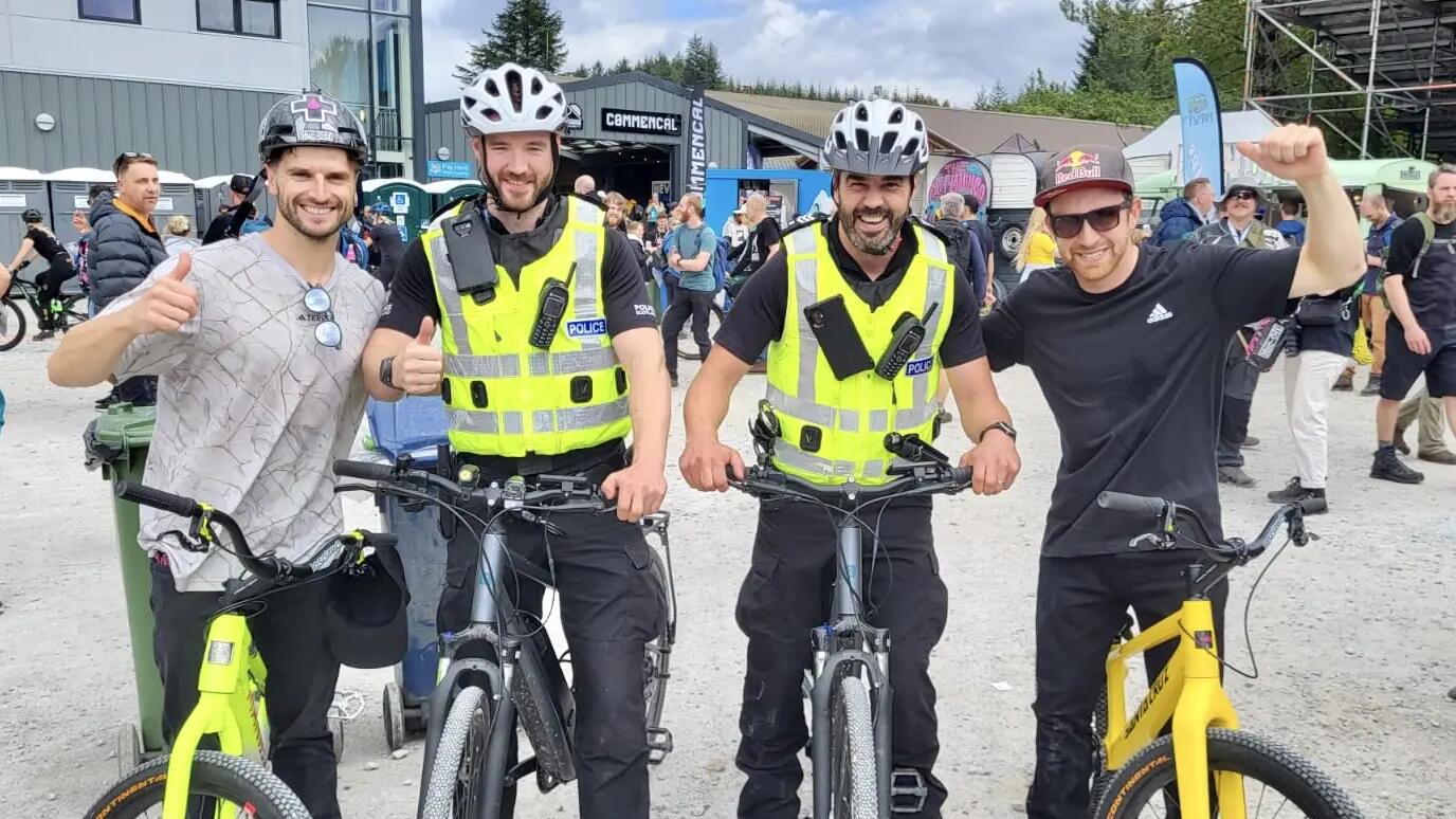 2 police and 2 civilian smiling at the camera 