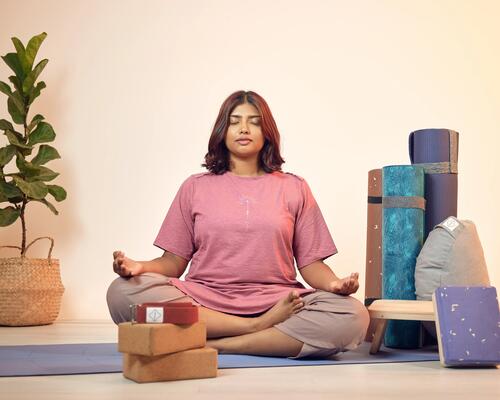 Kobieta siedząca na macie z założonymi nogami na siebie podczas treningu uważności mindfulness