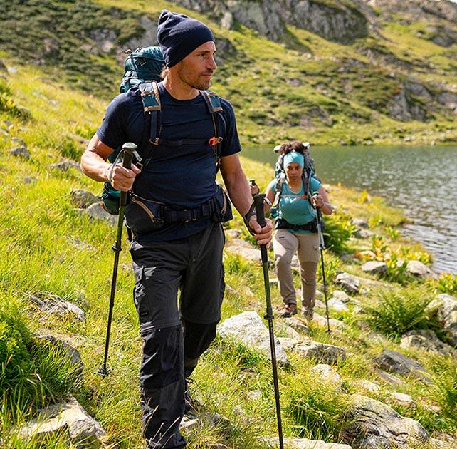 Ludzie wędrujący po górach w rozciągniętych butach trekkingowych z kijkami