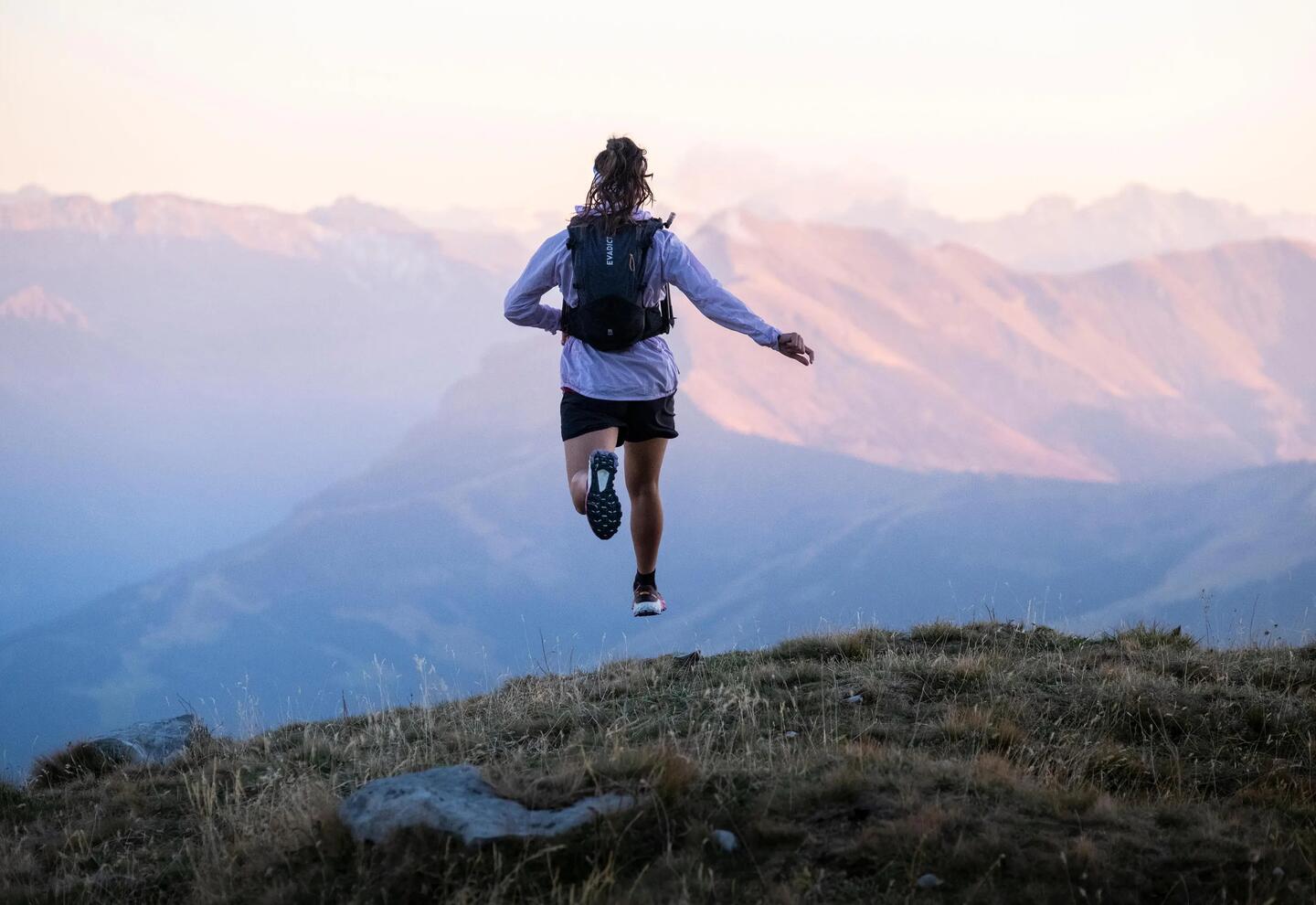 Trail-Runnerin in den Bergen bei Sonnenaufgang
