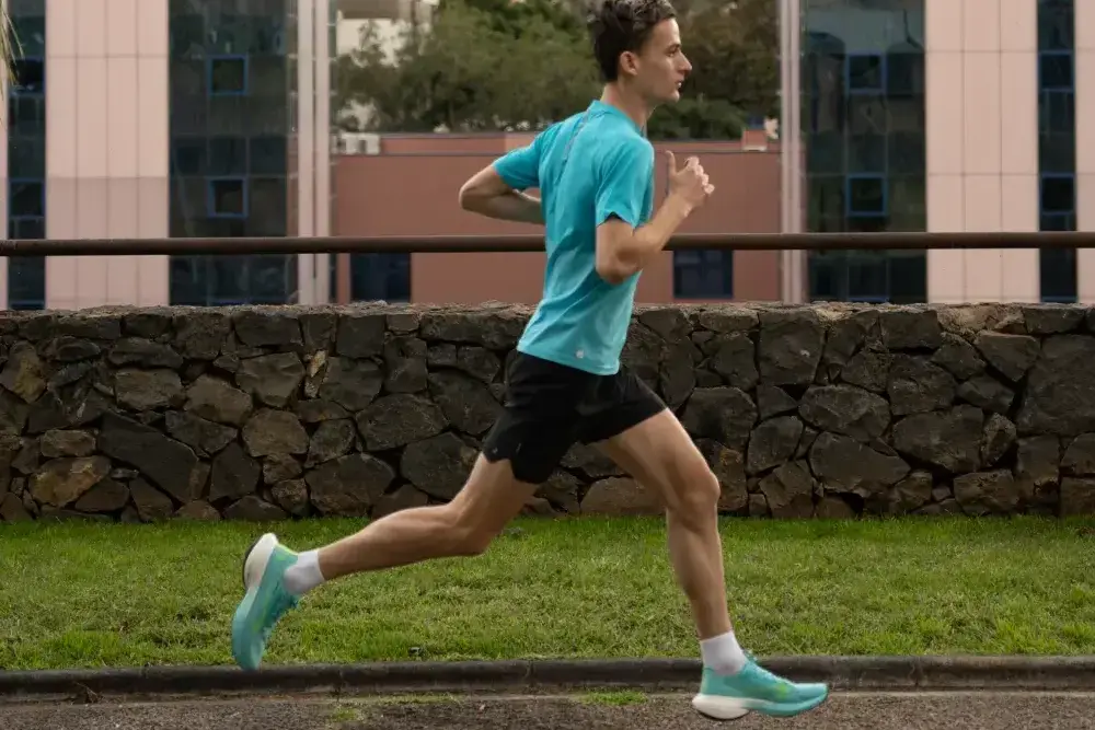 Mężczyzna biegający po bieżni na dworze w stroju i obuwiu sportowym