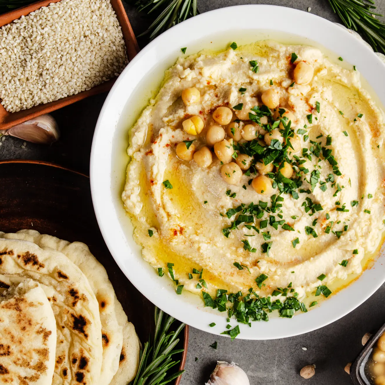 Hummus umieszczony w misce ozdobiony posiekaną pietruszką i cieciorką
