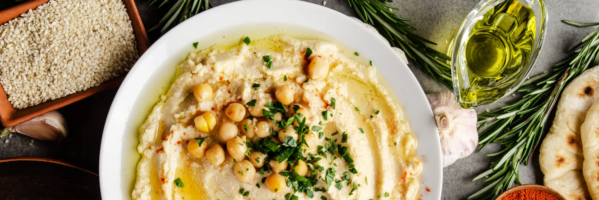 Hummus wegański zamiennik masła umieszczony w białej misce leżacy w otoczeniu wegańskich produktów spożywczych