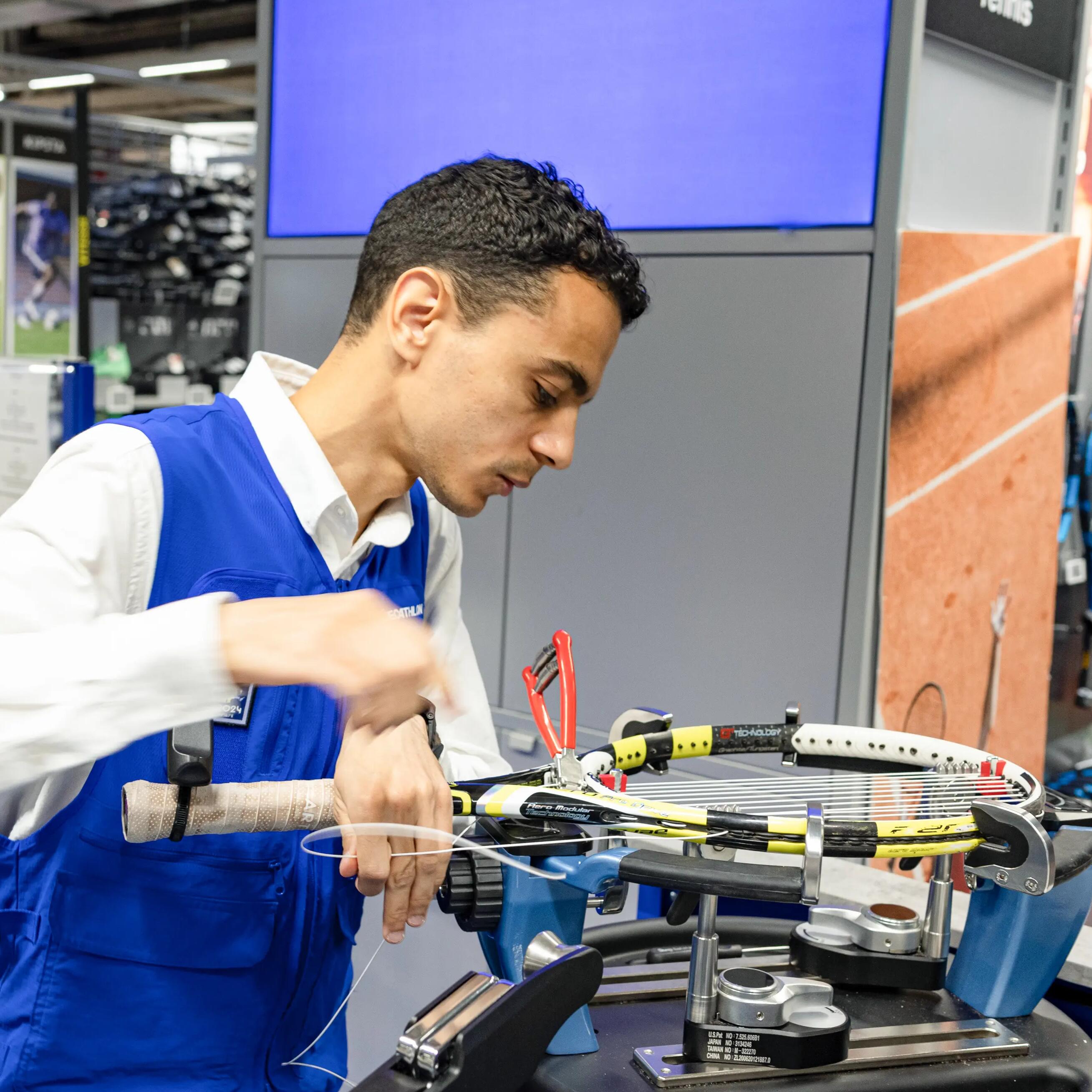 Técnico de taller Decathlon encordando una raqueta