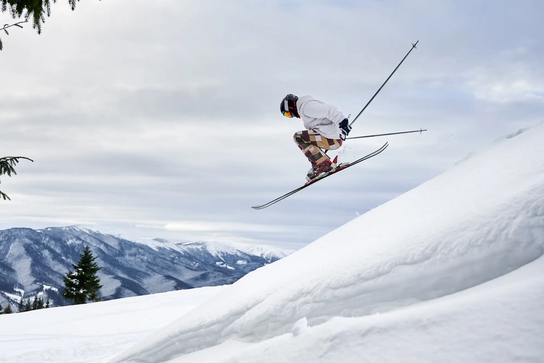 Narciarz w odzieży i kasku narciarskim trenujący freeskiing wykonując akrobacje w powietrzu