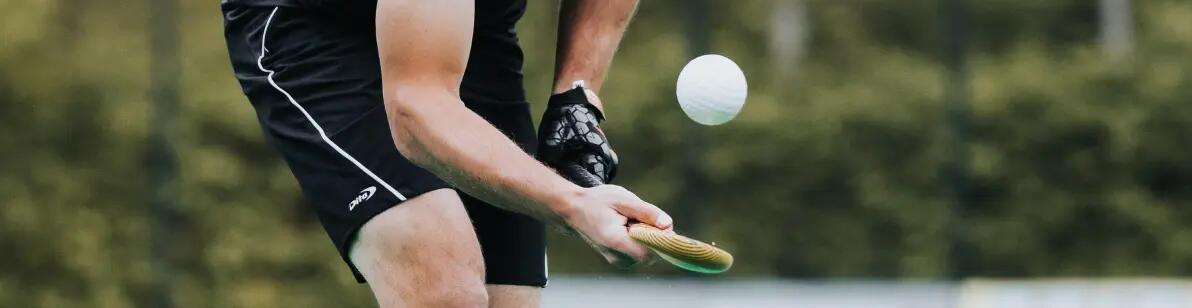 Iemand die een bal hoog houdt met een hockeystick op een veld