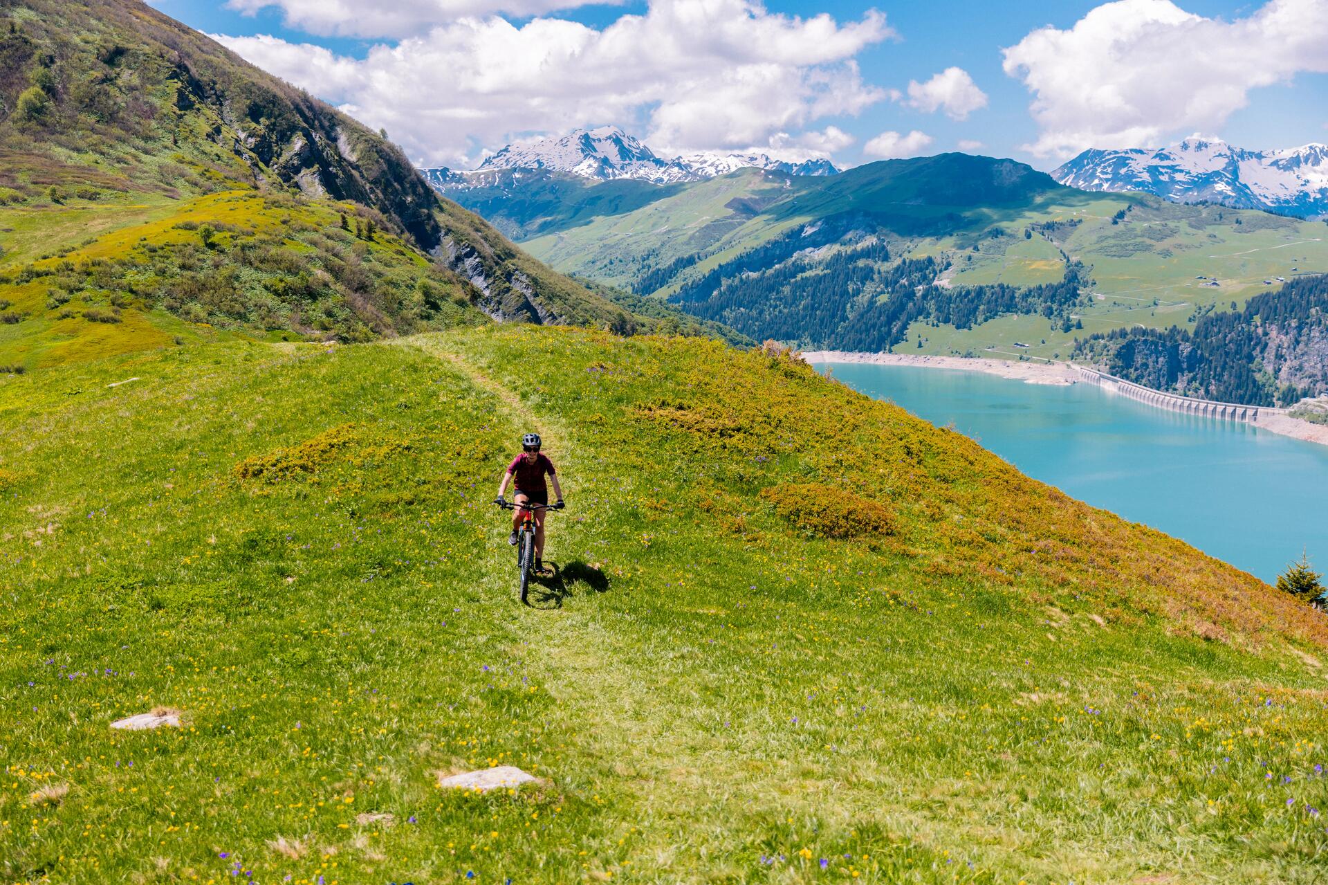 Kobieta w kasku i w okularach jadąca rowerem mtb po górach