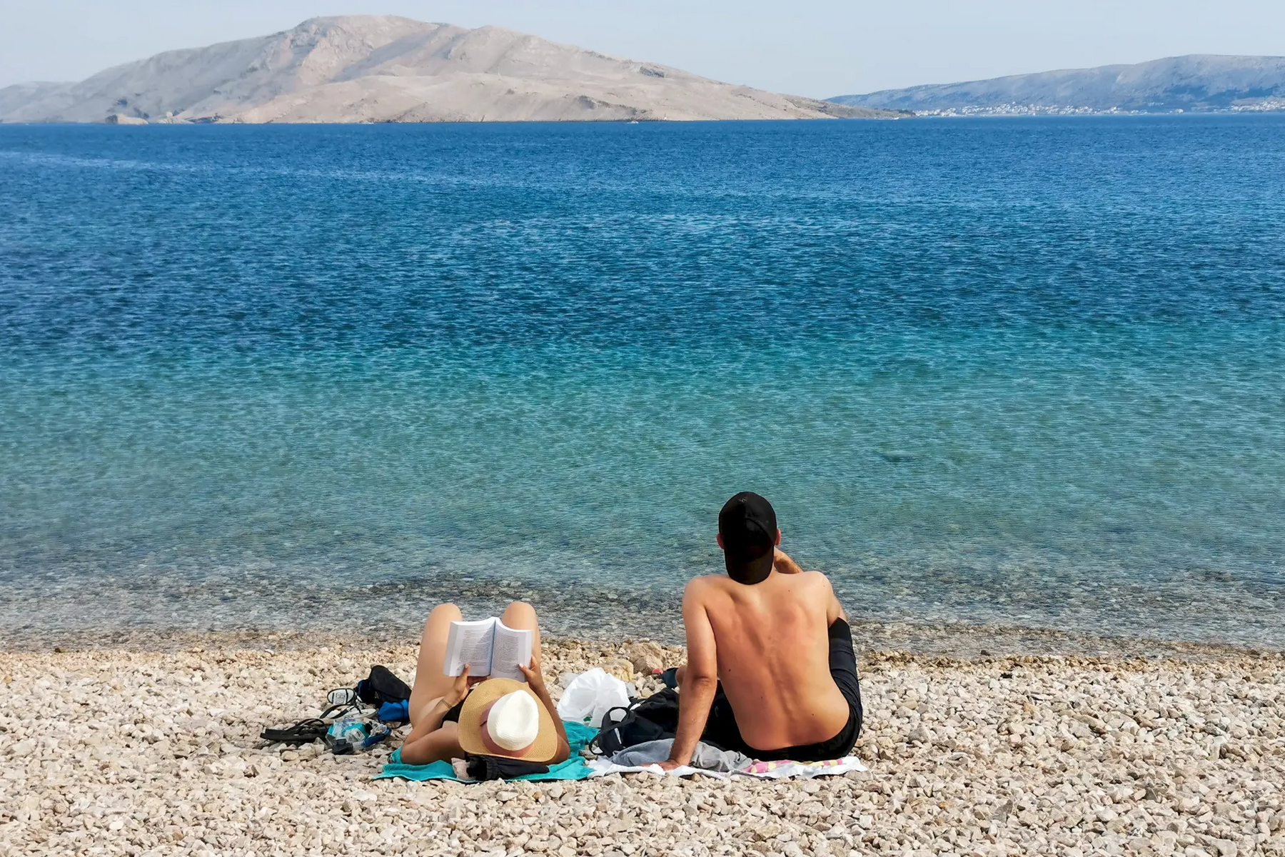 Para siedząca na plaży kamienistej na macie w Chorwacji relaksująca się na wakacjach