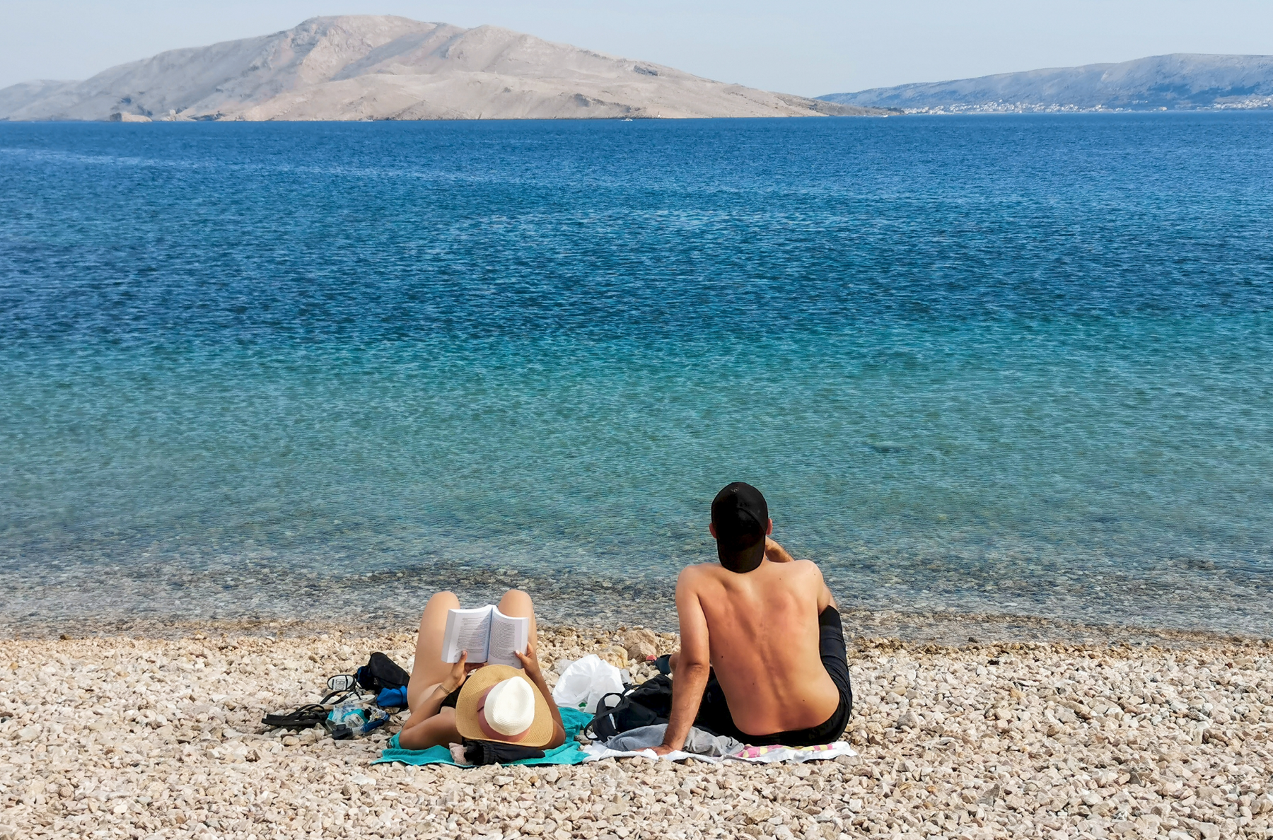 Para siedząca na plaży kamienistej na macie w Chorwacji relaksująca się na wakacjach
