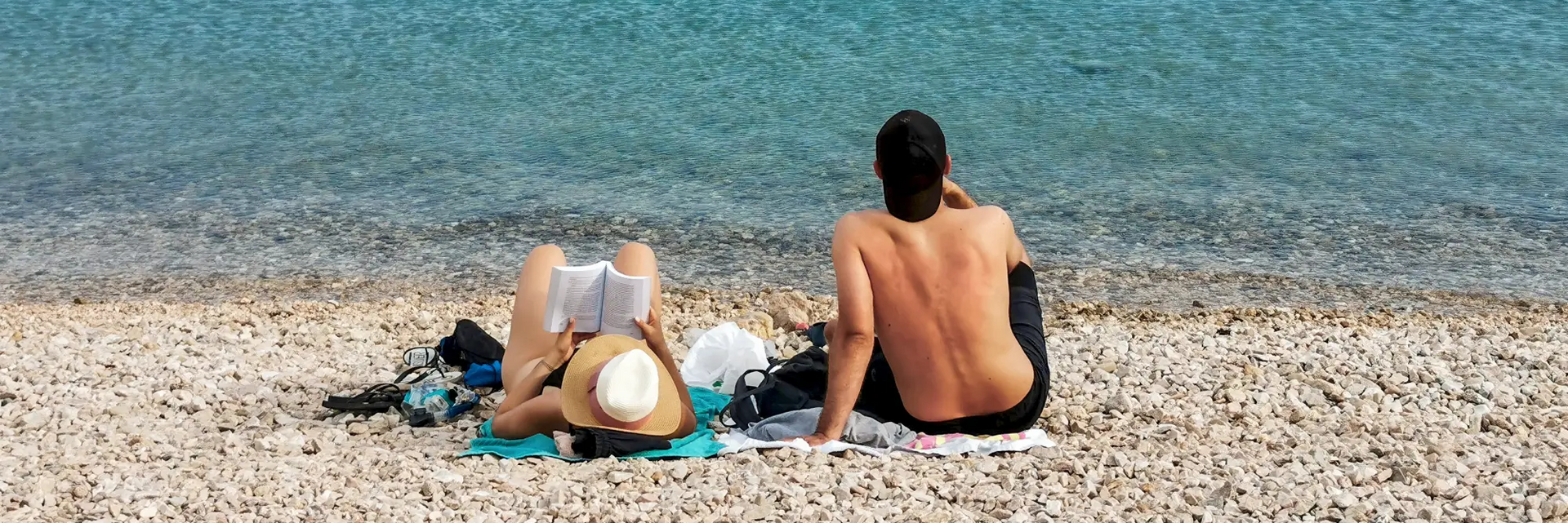 Para siedząca na plaży kamienistej na macie w Chorwacji relaksująca się na wakacjach