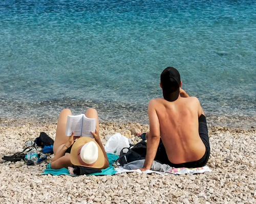 Para siedząca na plaży kamienistej na macie w Chorwacji relaksująca się na wakacjach