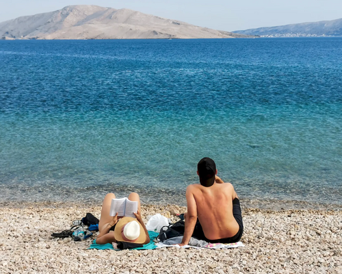 Para siedząca na plaży kamienistej na macie w Chorwacji relaksująca się na wakacjach