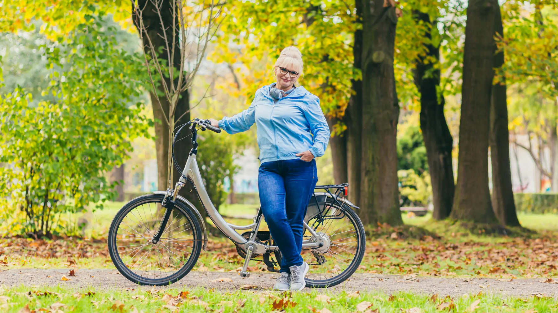 Kobieta stojąca przy rowerze w parku