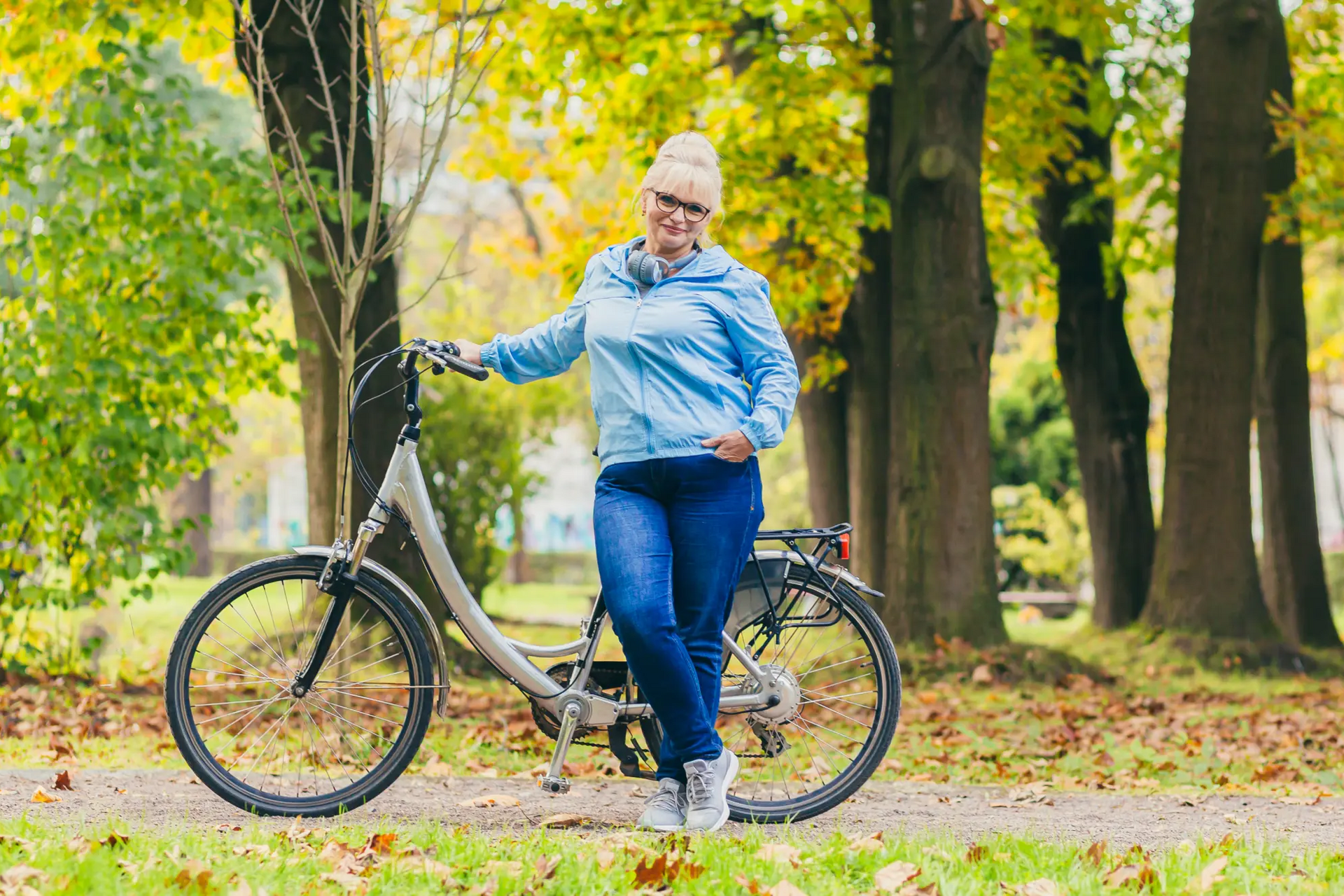 Kobieta z nadwagą stojąca przy rowerze w parku 