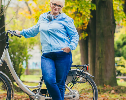 Kobieta stojąca przy rowerze chcąca zrzucić duży brzuch w okresie menopauzy