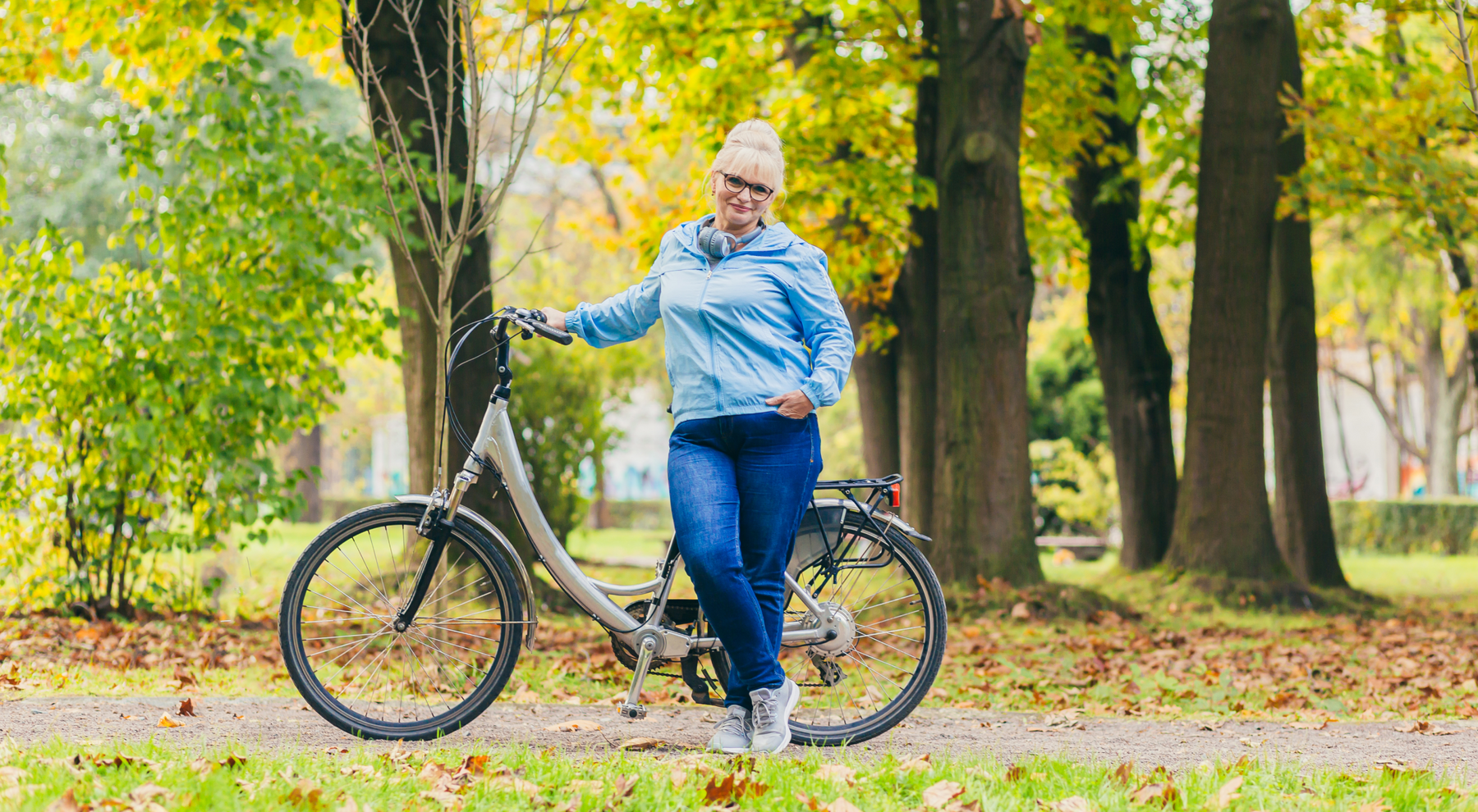 Seniorka stojąca przy rowerze w parku